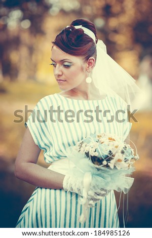 woman outdoor in vintage dress with bouquet of wildflowers. A woman in an retro dress in fairy park