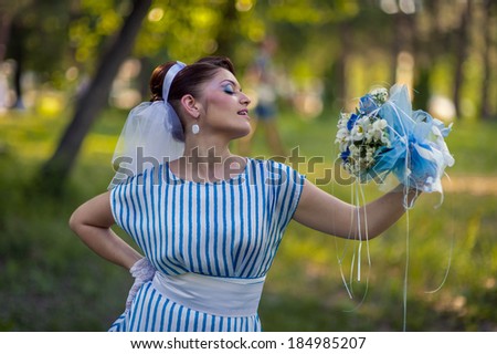 woman outdoor in vintage dress with bouquet of wildflowers. A woman in an retro dress in fairy park