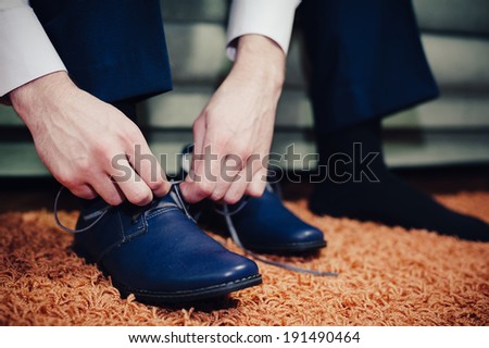 groom putting his wedding shoes. Hands of wedding groom getting ready in suit