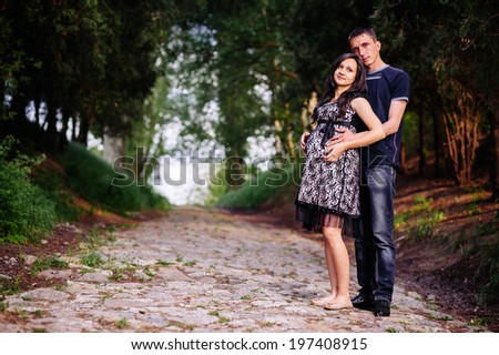 Portrait of beautiful loving couple awaiting baby. young happy family. Young family with a sun on the nature.