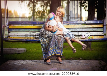 Picture of young mother hugging two little children, closeup portrait of happy family, cute blond female with daughter and son outdoor in spring time, smiling faces, happiness and love concept