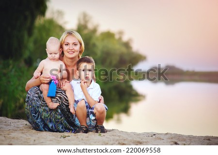 Picture of young mother hugging two little children, closeup portrait of happy family, cute blond female with daughter and son outdoor in spring time, smiling faces, happiness and love concept