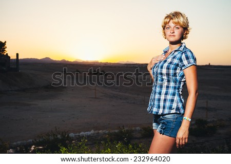 Sexy beautiful young woman at sunset in desert. Young woman walking outside in late evening desert sunshine. Ethereal image evoking dreamy freestyle fashion youth emotion