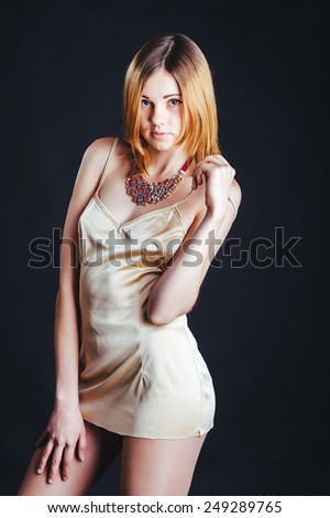 Sexy blonde Fashion Lady with messy hair in pastel beige dress isolated on black background. beautiful young blond girl posing on black studio background