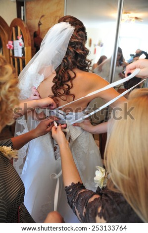 Bridesmaid is helping the bride to dress. bridesmaid tying bow on wedding dress.