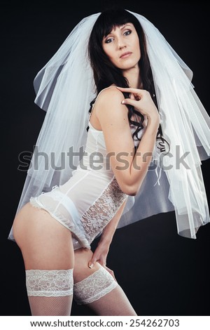 Sexy beautiful nude bride with veil in white erotic lingerie on a black background.