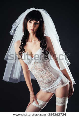 Sexy beautiful nude bride with veil in white erotic lingerie on a black background.