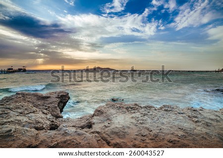 Wonderful solar Red Sea beach at a luxury hotel, at sunset. Sharm El Sheikh, Sinai, Egypt. Gold sunset with mountains and big wave.