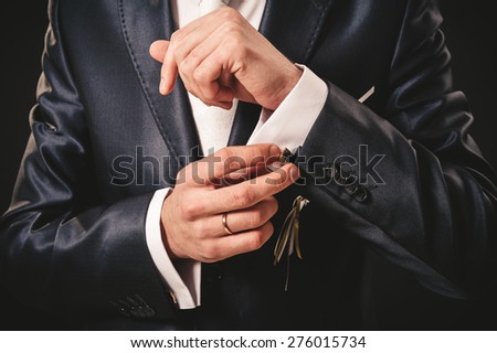 Hands of wedding groom getting ready in suit. black studio background.