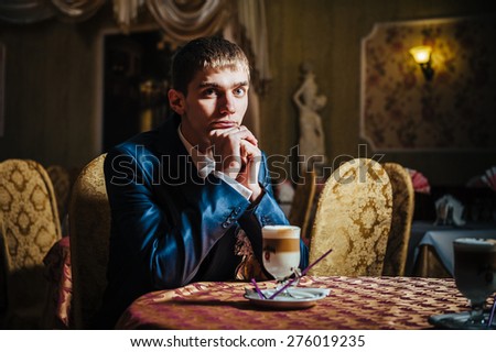 Groom\'s hands holding cup of coffee. Handsome man drinking coffee at in cafe
