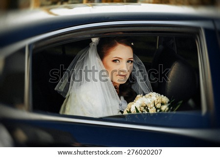 close-up portrait of a pretty shy bride in a car window.