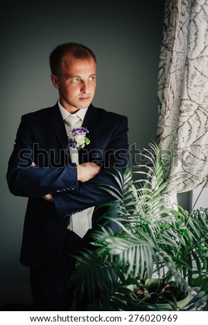 Portrait of a handsome groom in classical interior. The man in the white shirt in the window dress cufflinks