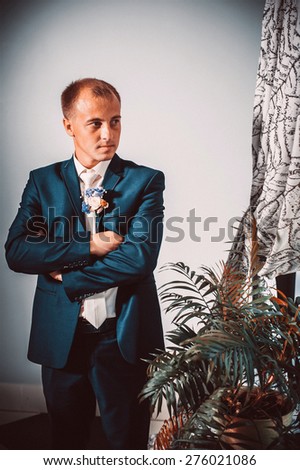 Portrait of a handsome groom in classical interior. The man in the white shirt in the window dress cufflinks