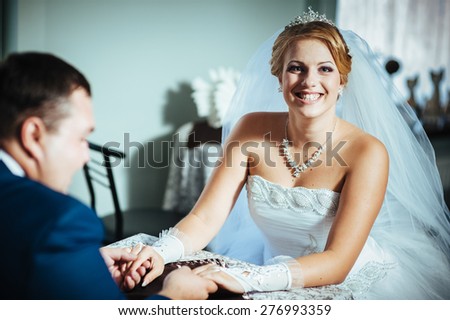 bride and groom are sitting at a table in restaurant. The groom\'s hand stroking his bride