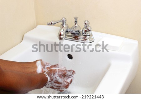 Person of color cleaning hands with soap and water