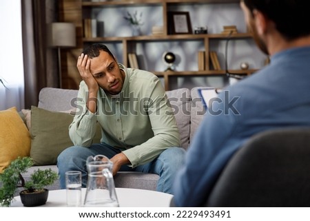 A visit to an African American psychologist. A man sits on a couch and talks to a psychotherapist. Depression, apathy, stress, burnout at work. Help of a psychologist. Сток-фото © 