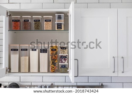 Kitchen storage organization use plastic case. Placing and sorting food products into pp box. Keeping organizing at modern kitchen interior in Nordic style. General cleaning, tidying up at cuisine