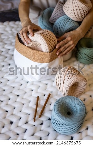 Female hands neatly putting hank reel ribbon yarn into basket for comfortable storage organization at home. Art woman arms doing spring seasonal tidying up assembling folded knitted wool container Stock fotó © 