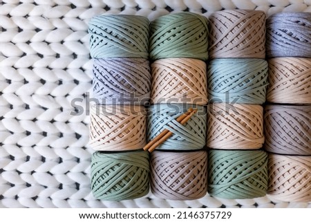 Top view pile of multicolored ribbon yarn hank reels neatly assembling in row on white woolen plaid. Art hobby or handmade design work. Seasonal tidying up storage organization Stock fotó © 