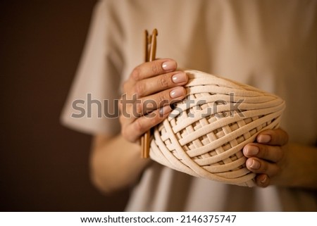 Closeup beautiful female hands hold hank reel of beige ribbon yarn and wooden crochet needles enjoying craft hobby or art work. Woman arms professional designer creating handmade clothes or accessory Stock fotó © 