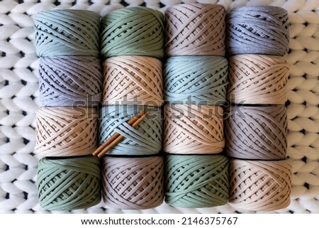 Top view pile of multicolored ribbon yarn hank reels neatly assembling in row on white woolen plaid. Art hobby or handmade design work. Seasonal tidying up storage organization Stock fotó © 