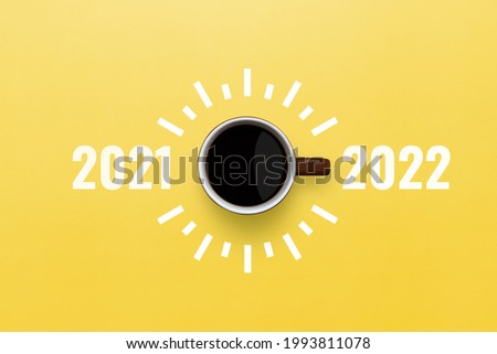 Happy new year 2022. Cup of coffee change 2021 to 2022 on yellow background. Start concept