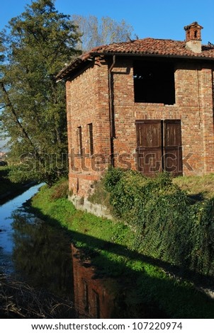 Old country house made with red bricks on a canal in a sunny day, Italy