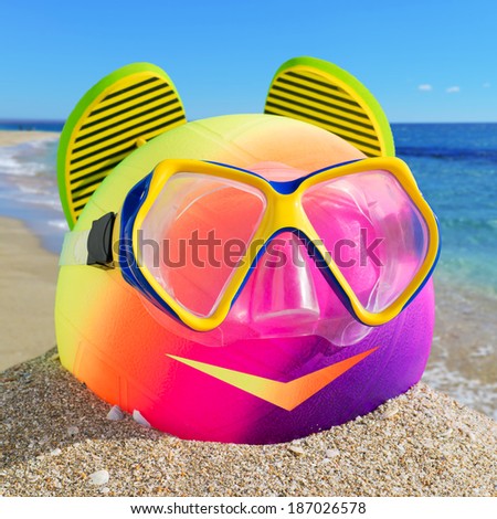 Smiling little man of beach accessories. Ball, flip-flop and diving mask on the beach against a blue sea and sky.