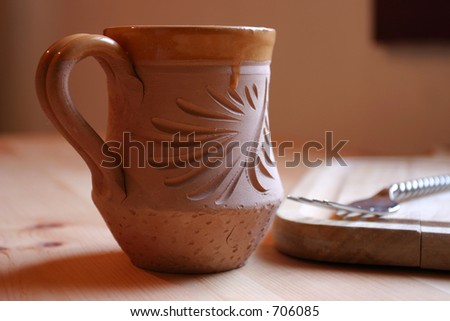 A cup of coffee on the edge of a table in the morning window light.