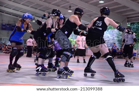 ANN ARBOR, MI - JULY 12: Ann Arbor Bruising Company defensive players prepare for the Northern Kentucky Shiners\' jammer\'s approach at their roller derby game in Ann Arbor, MI on July 12, 2014.