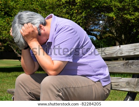 Middle-aged woman sitting on bench, head in hand in despair