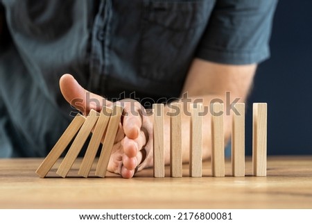Businessman hand stop falling off wood block, planing and strategy concept, business disruption, company restructuring, action needed Foto d'archivio © 