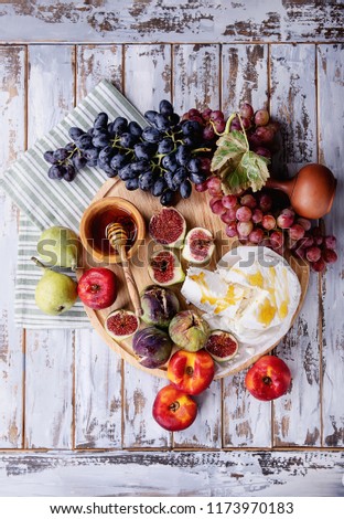 Home made ricotta cheese served with fresh fruit: figs, nectarines, grapes and pears decorated with honey and napkin over a rustic wooden board. Top View ストックフォト © 