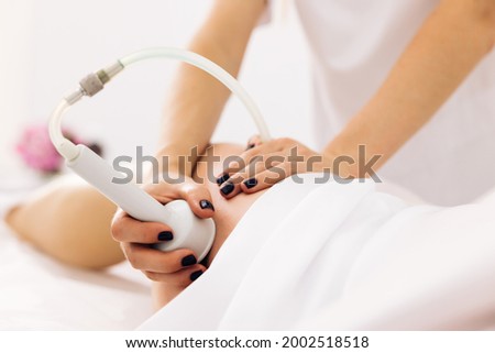Legs anti-cellulite procedures. Woman health and beauty. Hardware anti-cellulite massage. RF lifting procedure. The beautician guides the device along the client's leg Stok fotoğraf © 
