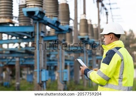 Energy business technology industry concept. Electrical engineer studying reading on tablet. Electrical worker engineer working with digital tablet near tower with electricity Foto d'archivio © 