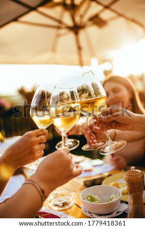 People clinking glasses with wine on the summer terrace of cafe or restaurant