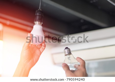 Power saving concept. Asia man changing compact-fluorescent (CFL) bulbs with new LED light bulb.
 Сток-фото © 