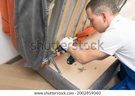 a furniture repair worker replacing the creaking mechanism of an upholstered sofa Foto d'archivio © 