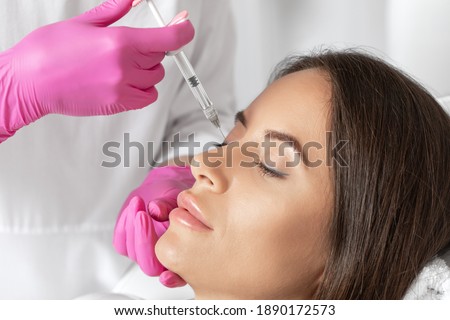 The doctor does injections to correct the hump on the nose with the beauty of the blonde. The beautician doees injections against wrinkles on the face. Women's cosmetology in a beauty salon. Imagine de stoc © 