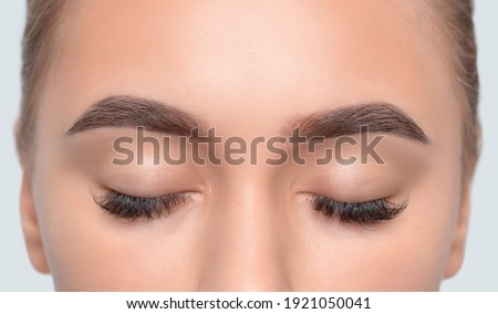 Eyebrows of a girl after plucking and cutting close-up. The make-up artist will do permanent eyebrow makeup. Makeup and cosmetology concept, eyebrow shape modeling.