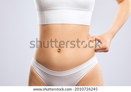 Girl pulls the skin on the abdomen, showing the body fat in the abdominal area and sides. Treatment and disposal of excess weight, the deposition of subcutaneous fat. ストックフォト © 