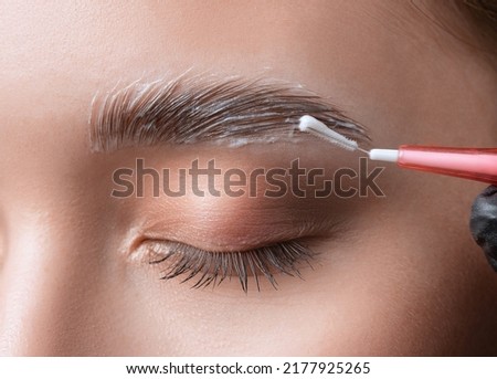 The make-up artist does Long-lasting styling of the eyebrows of the eyebrows and will color the eyebrows. Eyebrow lamination. Professional make-up and face care. Сток-фото © 