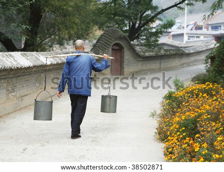 An old Chinese man is carring waters on his way back home.