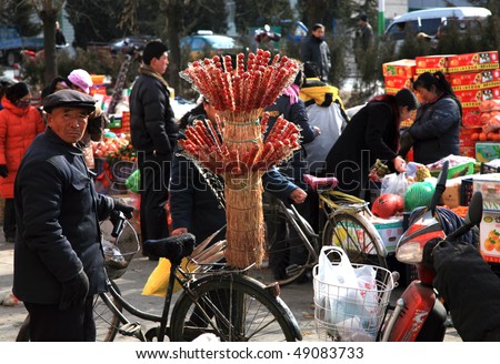 BEIJING, CHINA - FEBRUARY 18: A Chinese senior citizen sells tomatoes on sticks  in a country fair February 18, 2010 in Beijing, China.