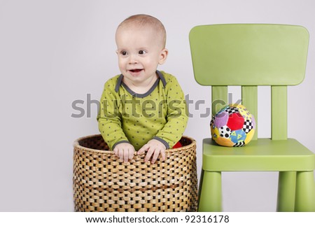 Baby boy in a basket with chair and ball