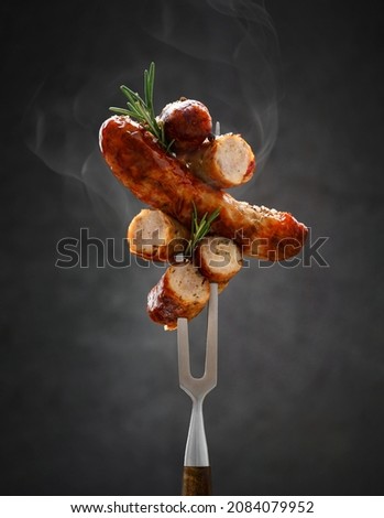 a whole and sliced grilled hot fried sausage is strung on a meat fork Imagine de stoc © 
