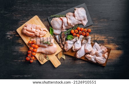 Prepared for frying, butchered various portions of raw chicken meat. Set of raw chicken fillet, thigh, wings, strips and legs on the background of the culinary table with spices and cherry tomatoes Stock foto © 