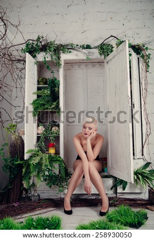 Naked blond woman is sitting in her closet. Concept : Nothing to wear