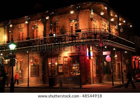 Brick building with balcony on the corner of St. Peter and Bourbon Streets at night in the French Quarter of New Orleans, LA