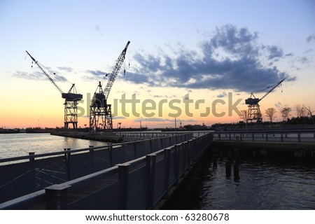 Three cranes on the pier silhouetted against the sunset in the harbor at Erie Basin Park at Red Hook Brooklyn - Brooklyn, NY